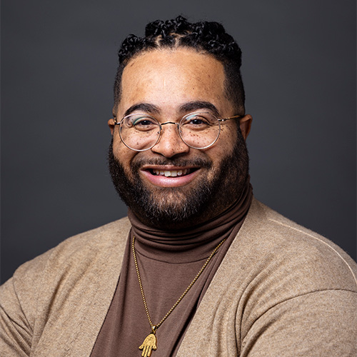 Chris Carr who has braids and wears a brown cardigan